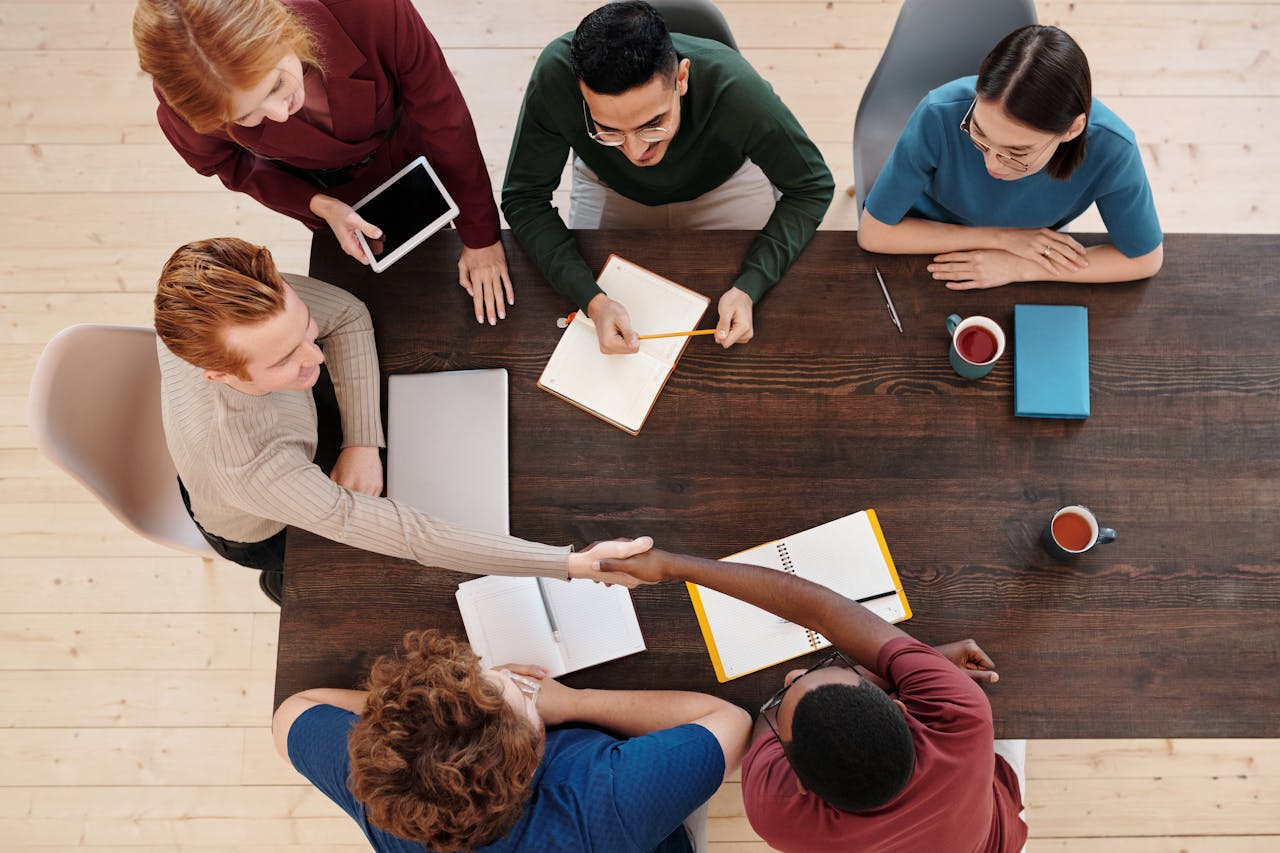 hero-img-01 Top view of a diverse business team meeting with a handshake across the table. Collaborative working environment.